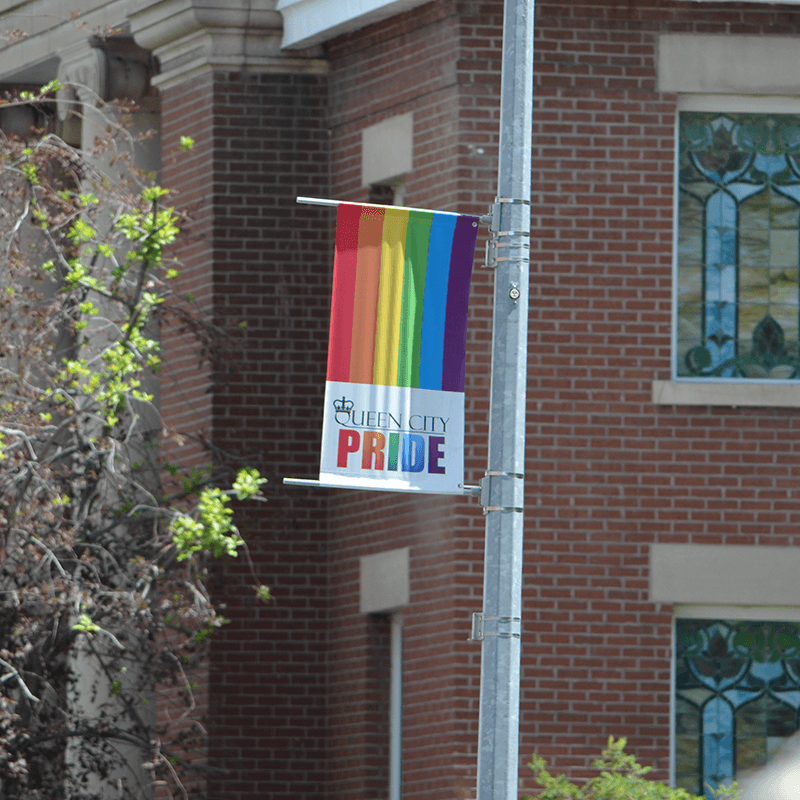 A rainbow-coloured streetlight banner with Queen City Pride's logo on display on a light pole in downtown Regina